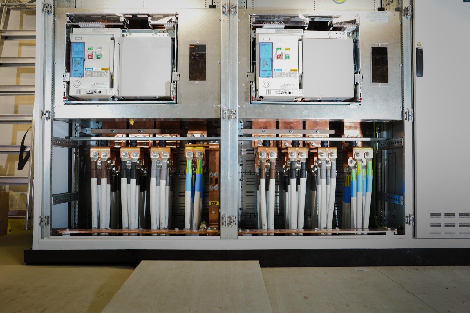 Circuit breakers, copper busbars, wires and components for power distribution and control are clearly arranged in an open electrical panel.