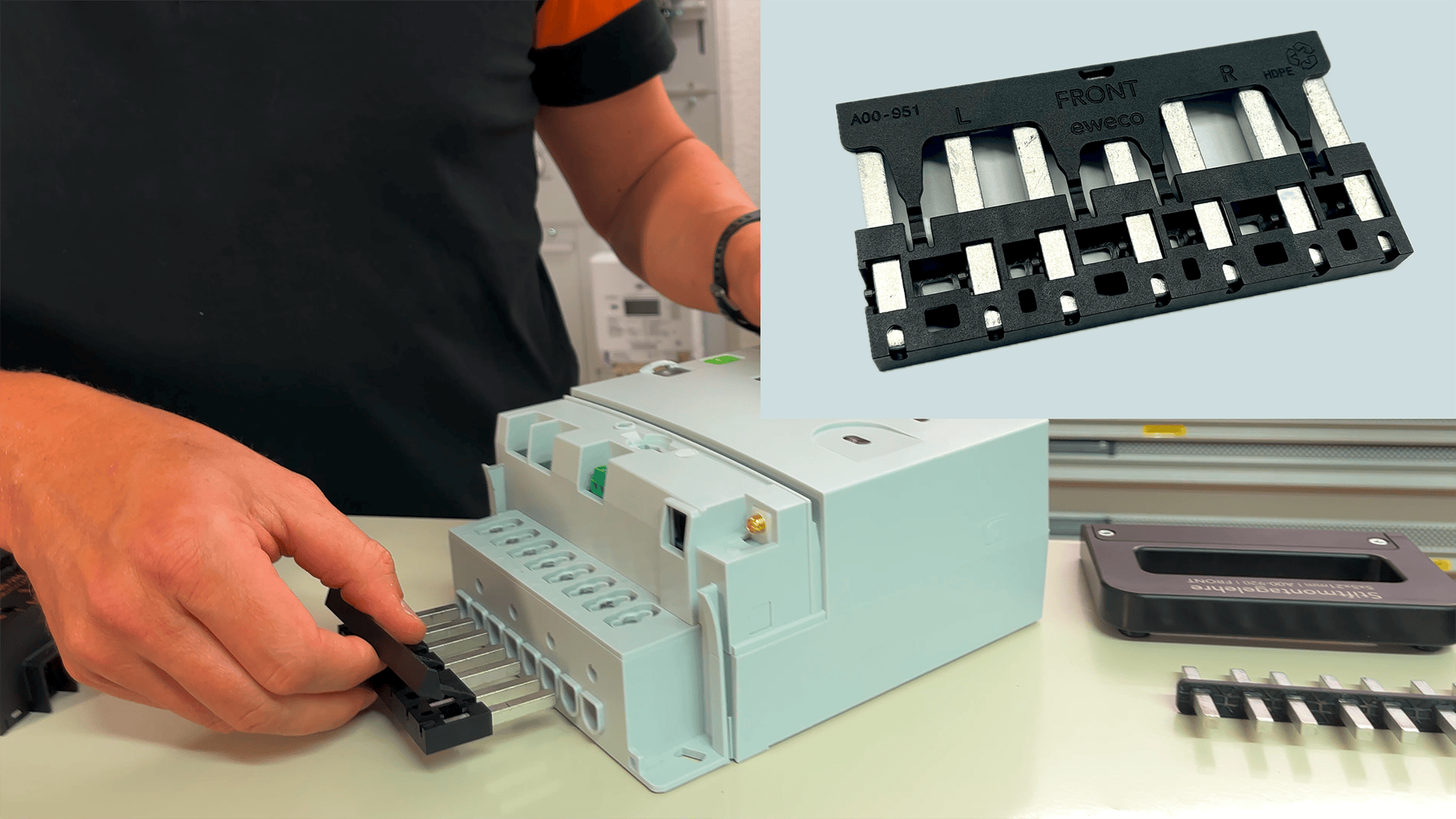 Eine Person steckt einen schwarzen Stecker in ein graues elektrisches Gerät. Ein Einschub zeigt eine Nahaufnahme des Steckers mit Metallkontakten und dem Wort "FRONT" mit Richtungspfeilen.