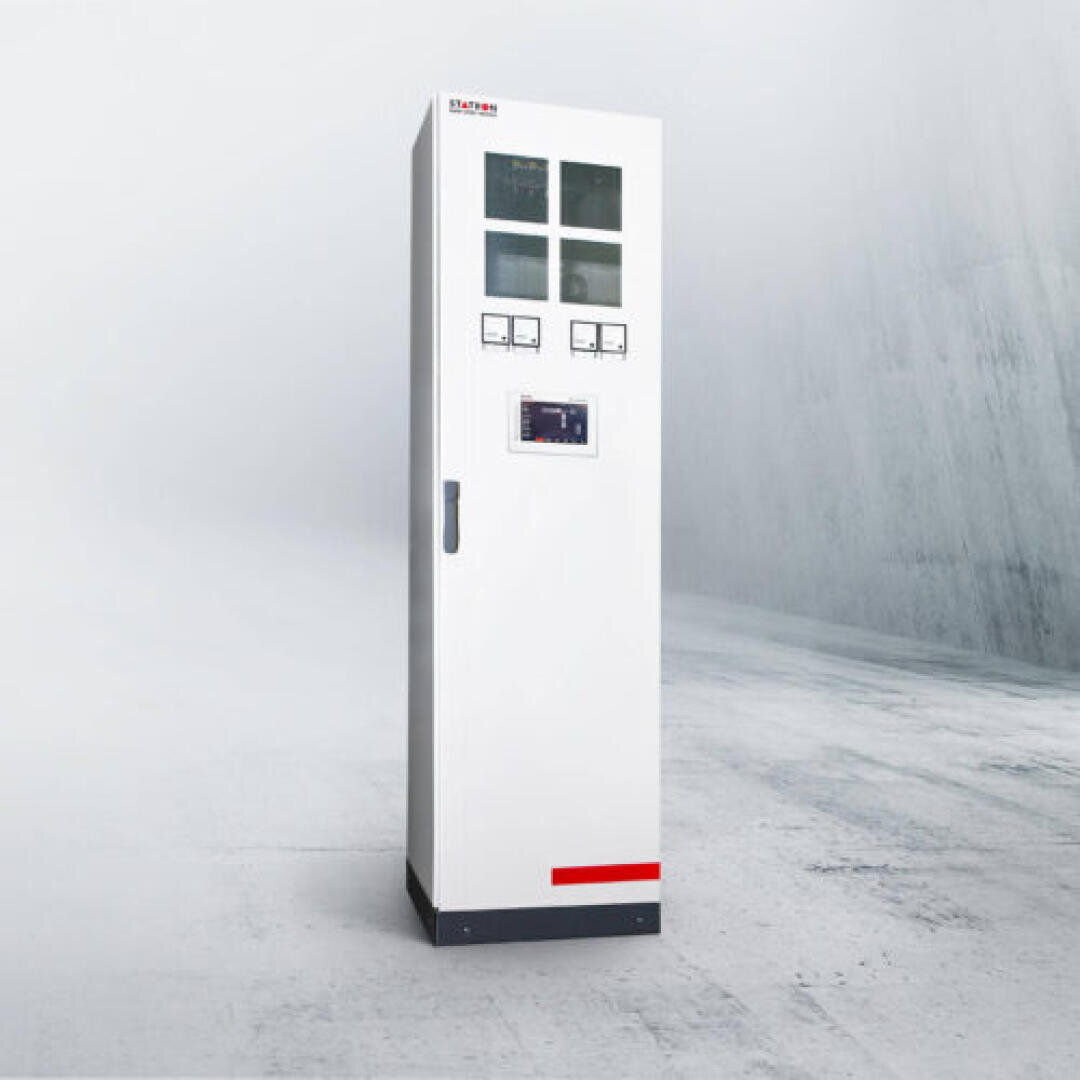 A tall, white control cabinet with meters and screens on the front, standing on a clean, empty concrete floor in a minimalist, gray-tinted room.